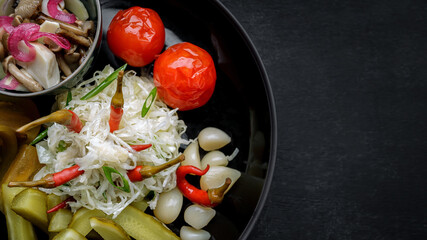 Assorted pickled vegetables on a black plate