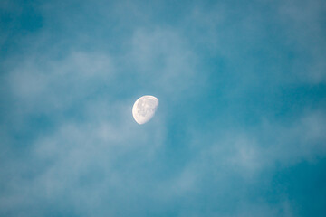 blue sky with white clouds and half moon at morning