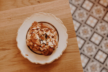 Breakfast time. Sweet cake with cream, almonds on a beautiful plate on a wooden table