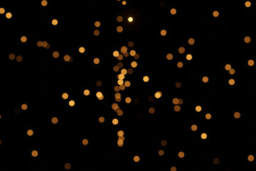 Defocused bokeh lights on black background, an abstract naturally blurred backdrop for Christmas eve or birthday party. Festive light texture. Yellow and red garland in blur. Overlay effect for design