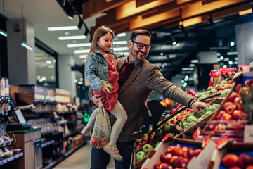 Father and daughter buying apples in grocery store - 495991325