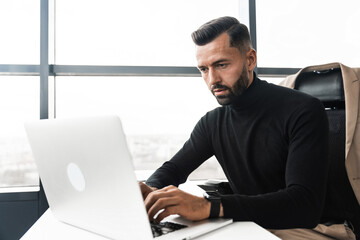Focused businessman working on laptop while sitting in office