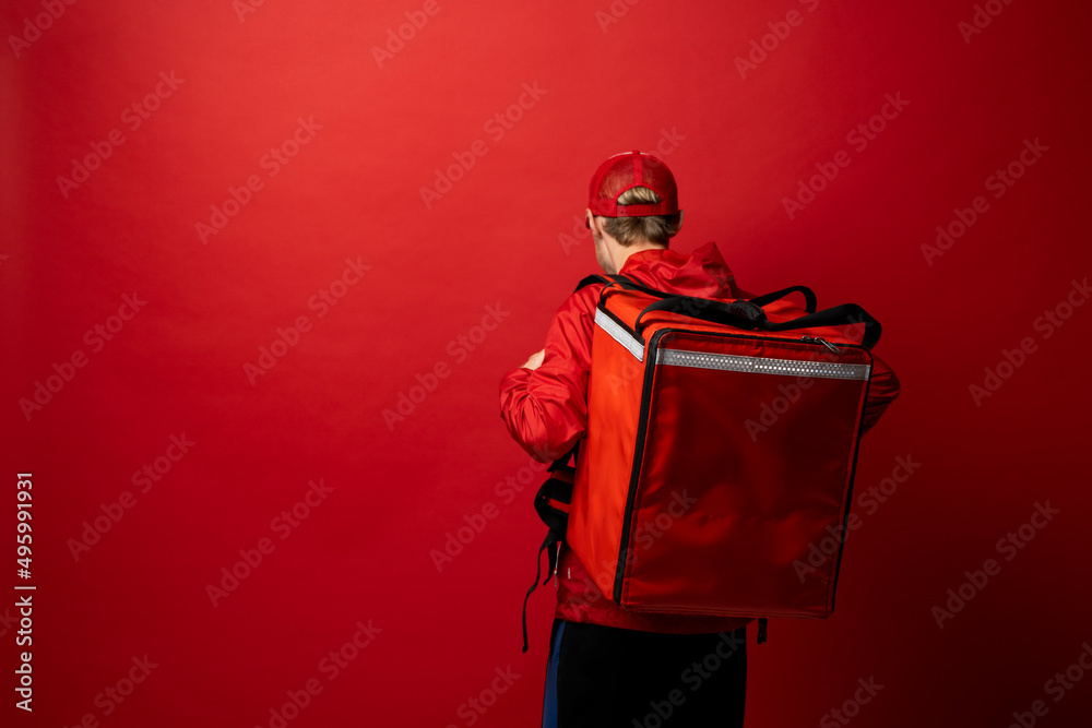 Sticker Delivery man in red uniform with a thermal backpack isolated on a white background. Fast home delivery. Online order. Courier delivers groceries home.