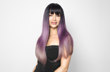 Fototapeta premium Beautiful young woman with perfect skin and long shiny purple hair at white background. Coloring and toning hair