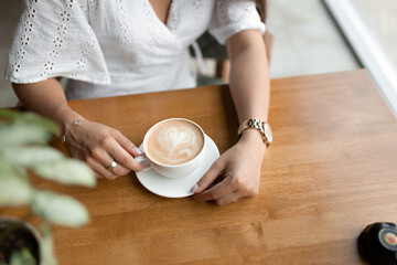 hands of a girl with a cup of coffee in a cafe