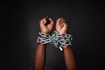 I want to break free. Cropped shot of a mans hands tied up with chains against a black background.