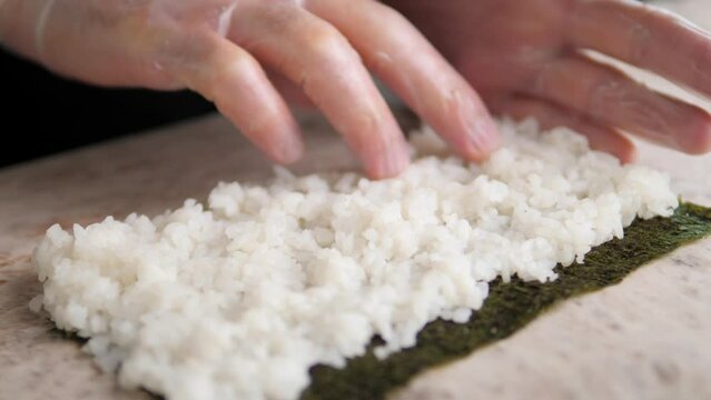 a sushi filling is applied to a bamboo mat. rice is shaped to make sushi. Asian cuisine. sushi cooking