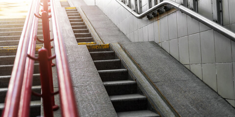 Urban stair with stone steps and red handrail leading up at city street