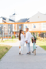 loving couple walks around the city with a bicycle and a basket of flowers