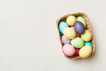 Multi colors Easter eggs in the woven basket on colored background . Pastel color Easter eggs. holiday concept with copy space