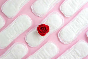 Pattern of women's monthly pads and one red rose. The concept of female menstruation. Selective focus, top view, copy space