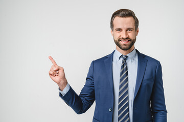 Toothy smile of handsome caucasian successful confident businessman in formalwear suit pointing showing copyspace free space isolated in white background