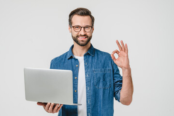 Happy successful caucasian young man freelancer student showing okay gesture, using laptop for...