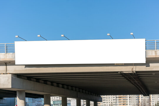 Long white empty signboard hanging on concrete urban bridge for commercial information and advertise message