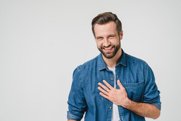 Fototapeta Happy young caucasian man in denim clothes laughing, touched with a compliment, good sense of humor isolated in white background obraz