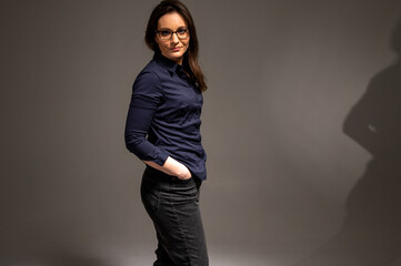 Portrait of a beautiful, emotional, interesting cheerful brunette with glasses who thinks too much, looking straight, isolated on a homogeneous background