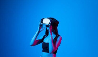 Smile happy woman getting experience using vr-headset glasses of virtual reality much gesticulating hands on gray background. Girl spend shes time in metaverse.