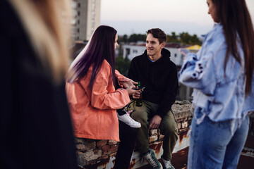 Three teenage friends sitting on the rooftop, chilling and drinking beer.