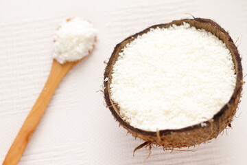 Fototapeta na wymiar Coconut flakes in coconut shell and wooden spoon, natural ingredients