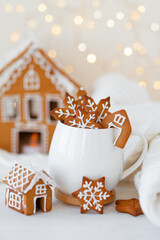 Hot winter drink in a white mug: cozy home composition with homemade gingerbread cookies, candy...