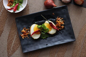 Egg with Tamarind Sauce in a white plate served on a wooden table with coriander sprinkles, is a popular local dish that Thai people eat.