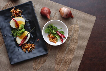 Egg with Tamarind Sauce in a white plate served on a wooden table with coriander sprinkles, is a popular local dish that Thai people eat.