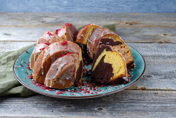 Traditional exotically bundt marble cocoa chocolate cake with icing sugar glaze and freeze dry raspberry topping served as close-up on a Nordic design plate with copy space