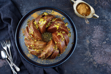 Exotically bundt marble passion fruit rum cake with icing sugar glaze, fresh fruit pulp topping and muscovado brown sugar served as top view on a plate with copy space