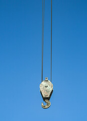 Crane hook on a blue sky. Crane hook. Crane hook on the background of a blue, cloudy sky.