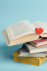 Old vintage books and heart shape wooden piece. World books day. Copy space. Education concept. Vertical photo