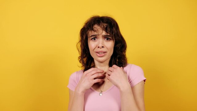 Beautiful afraid brunette lady scaredly closing face with hands. Attractive young girl on yellow background. High quality 4k footage