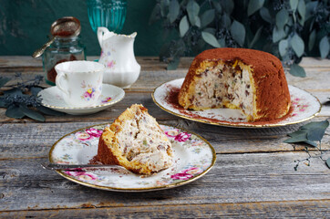 Traditional Italian Panettone cake stuffed with ricotta pudding, glanced fruits and raisins served as close-up on a classic design plate