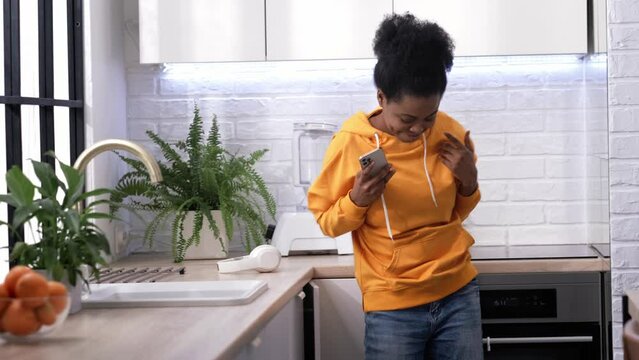 Dancing African American Girl using smartphone pressing finger, reading social media internet, typing text or shopping online Mobile phone in two black hands 