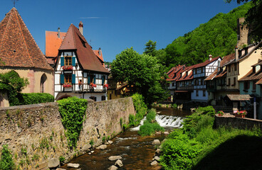 Fototapeta na wymiar Beautiful Timbered Houses At The Weissbach Creek In Kaysersberg Alsace France On A Beautiful Sunny Spring Day With A Clear Blue Sky