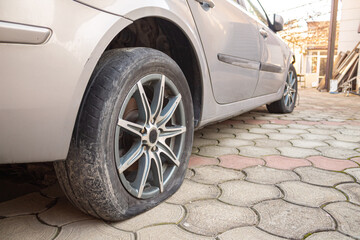 Naklejka premium flat tire accident in car park on the street waiting for repair. Flat tire and spare concept