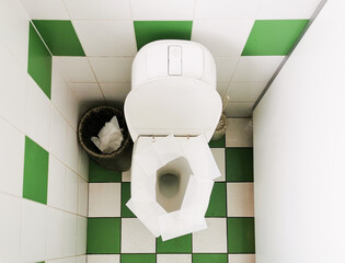 Napkins on the toilet seat in a public restroom. Toilet paper on the toilet seat.