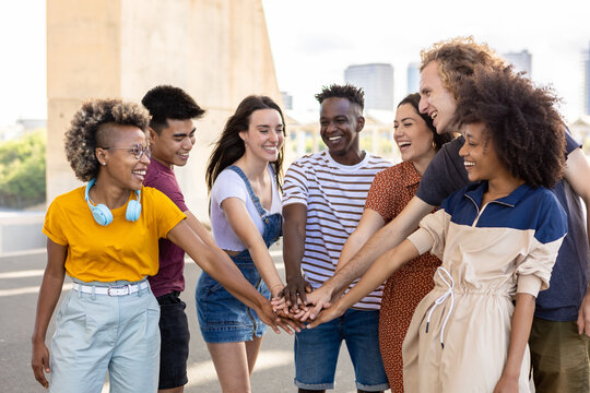 Group of young student friends with hands on stack showing international unity. United multiracial students standing together in city street - Community concept