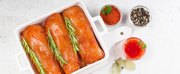 Marinated Chicken Breast with spices and rosemary. Raw meat in the marinade.