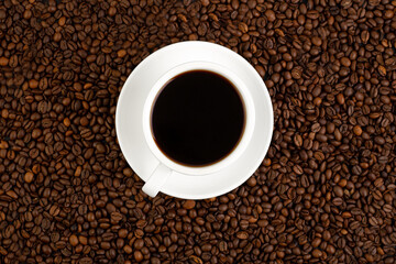Fresh roasted coffee bean background with a white cup of hot filter coffee, espresso. Banner, Flat lay, top view, background coffee beans
