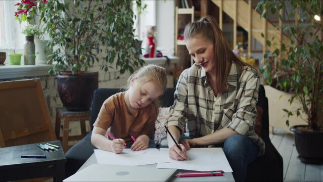 A woman spends time with her daughter. She draws with her and gives advice