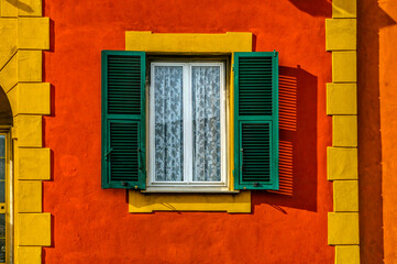 Window with green shutters and a bright orange wall