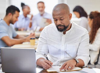 The man in charge of big plans. Shot of a mature businessman writing notes while working on a...