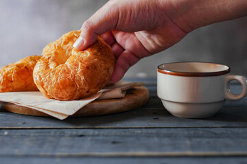 Croissant served with coffee on a black wooden table.