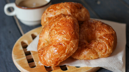 Croissant served with coffee on a black wooden table.