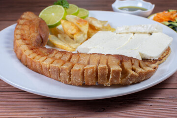 Typical Colombian food, chocolo arepa with cheese, pork chicarron French fries, chimichurri and salad