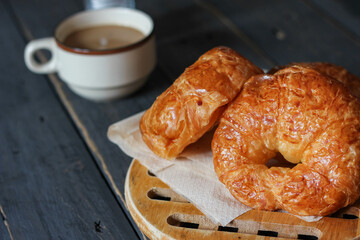 Croissant served with coffee on a black wooden table.