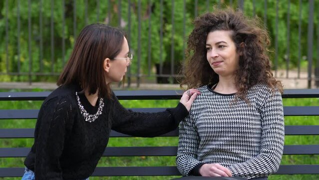Woman helping depressed friend. Young adult together in park. Girls comforting sad friend