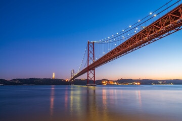 Fototapeta na wymiar The 25 de Abril bridge over the Tajo River with Cristo Rei or Christ the King in the background. Lisbon. Portugal