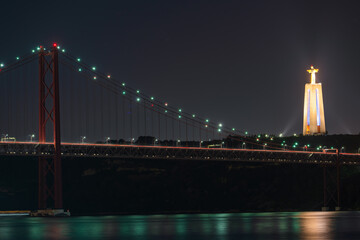 Fototapeta premium The 25 de Abril bridge and Cristo Rei or Christ the King statue at night in Lisbon. Portugal