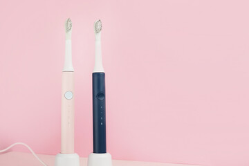 Two new modern ultrasonic toothbrushes. Dental care supplies on pink pastel background. Oral hygiene, dental and gum health, healthy teeth. Dental products Ultrasonic vibration toothbrush.